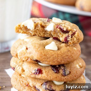 Cranberry White Chocolate Cookie Recipe for Festive Baking 5 Stack of white chocolate cranberry cookies with the top cookie broken in half.