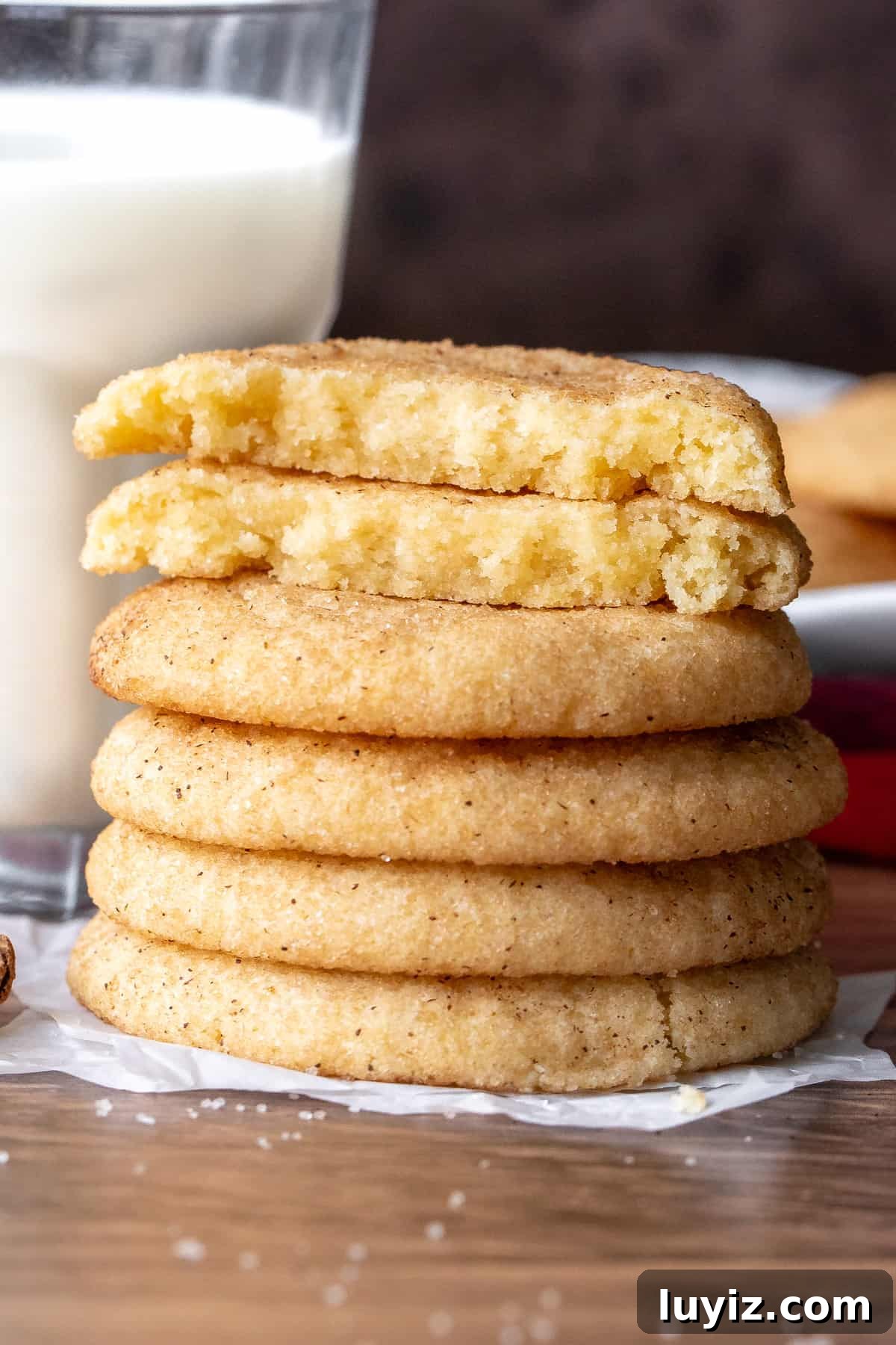 Chewy Snickerdoodle Cookies: A Classic Cinnamon Sugar Recipe 9 Stack of snickerdoodles with top cookie broken in half beside glass of milk