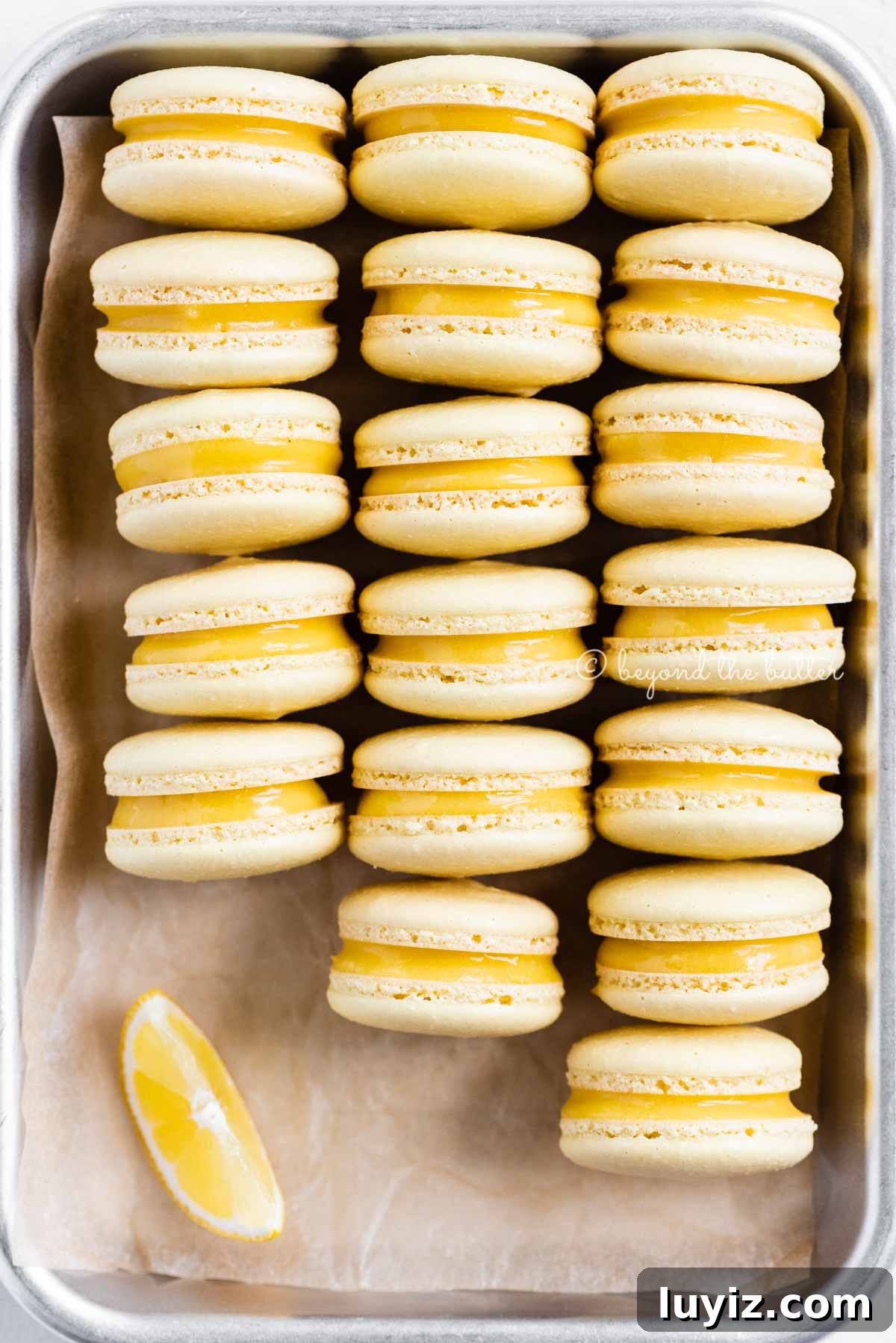 Zesty Lemon Bar Macarons: Tangy Citrus Sandwich Cookies 11 Close up of lemon bar macarons on side on a baking tray | All Images © Beyond the Butter™