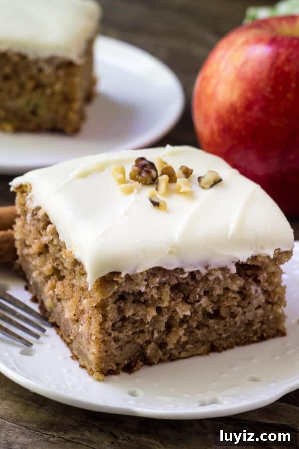 Top 10 Most Memorable Recipes of 2017 You Need to Try 6 Slice of apple spice cake with cream cheese frosting topped with chopped walnuts. Apple and second slice of cake in the backround.