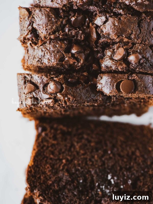 Moist Chocolate Zucchini Cake Recipe with Cocoa and Oil 10 Sliced chocolate zucchini bread on white background.