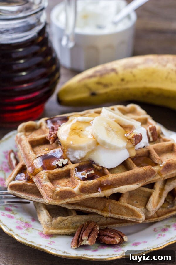 Cinnamon-Stuffed Banana Bread Waffles — Light & Fluffy 4 A stack of banana waffles drizzled with maple syrup and topped with whipped cream, chopped bananas & pecans.