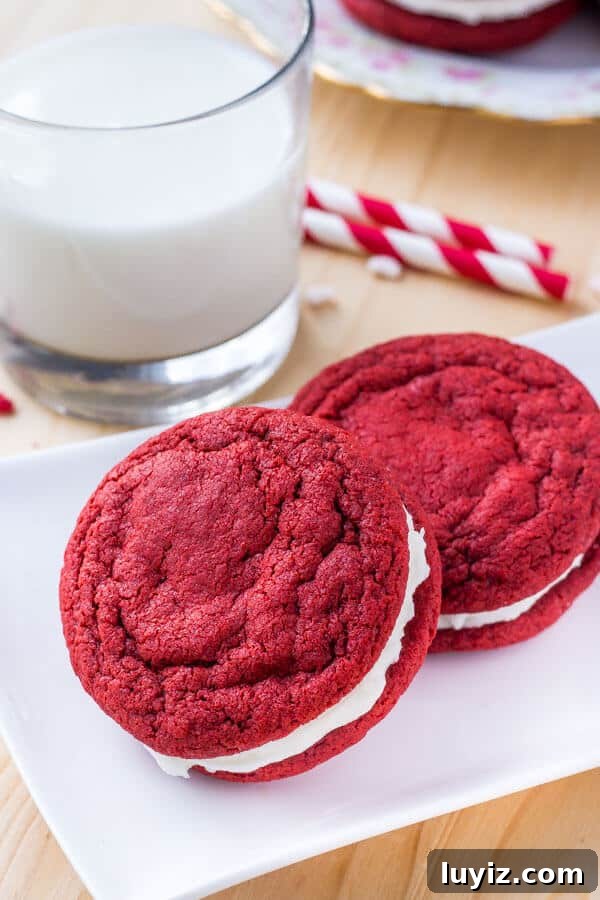Red Velvet Sandwich Cookie Recipe — Soft Cream-Filled Cookies 2 Two homemade red velvet sandwich cookies with cream cheese frosting.