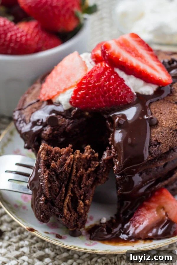 A stack of fluffy chocolate pancakes drizzled with chocolate ganache