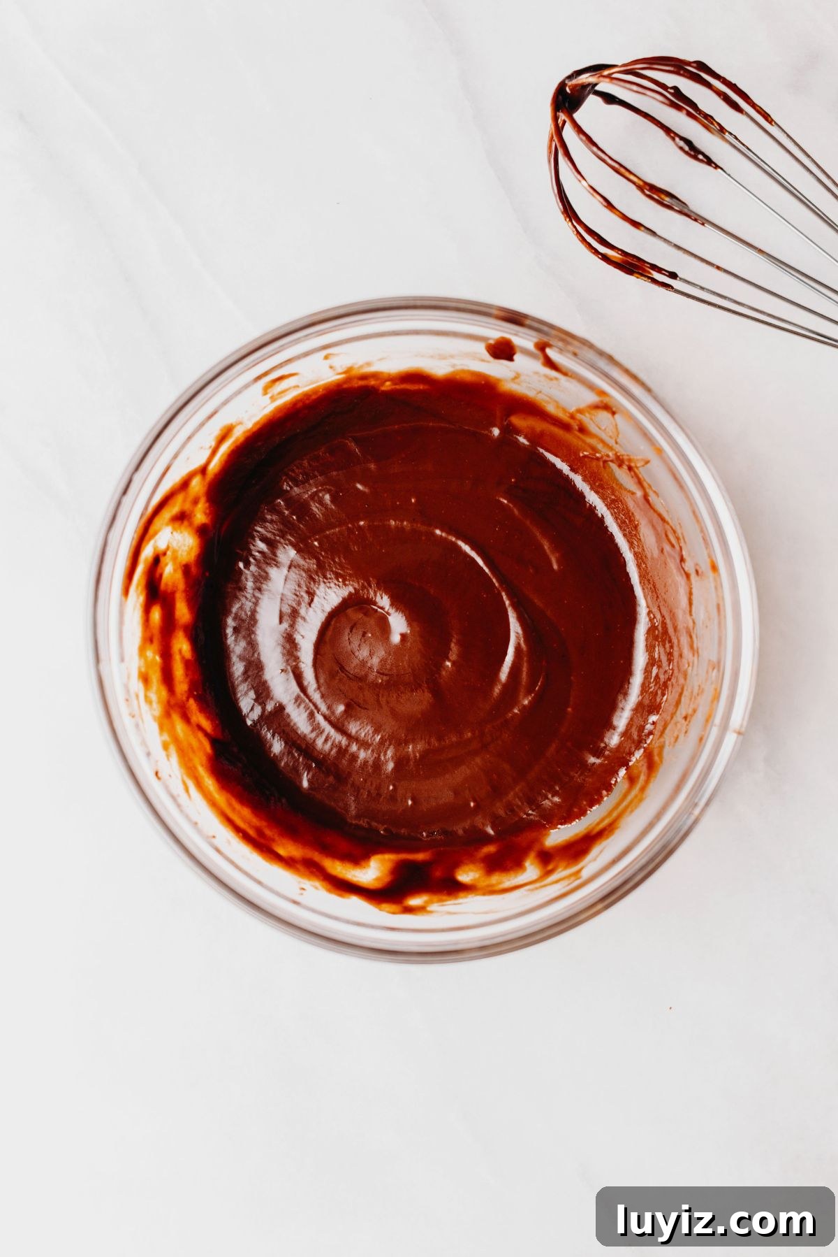 Decadent Marble Bundt Cake Recipe with Swirled Chocolate-Vanilla 13 Whisked chocolate ganache glaze in a glass mixing bowl with a whisk placed off to the side.