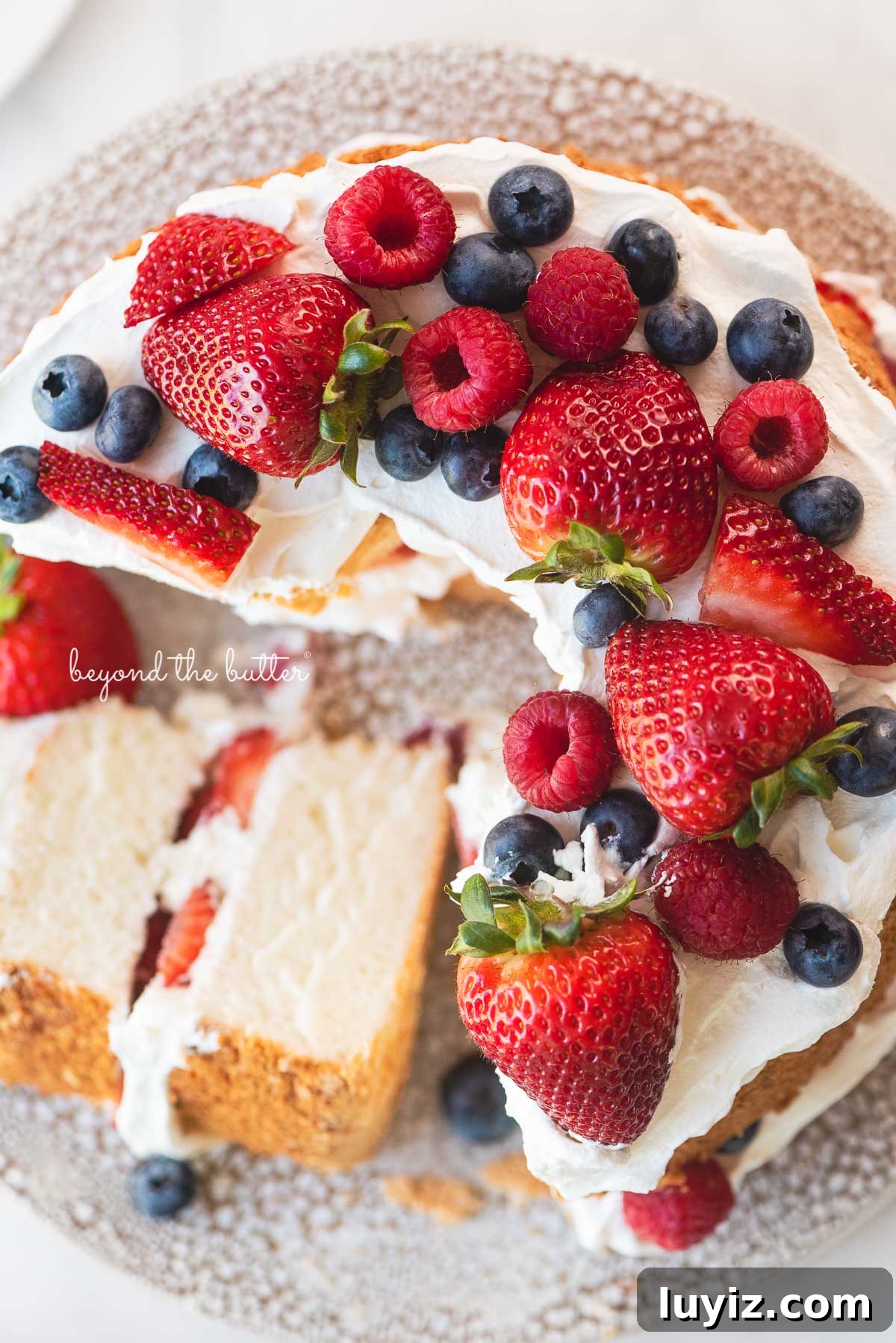 Light and Fluffy Homemade Angel Food Cake Recipe 4 Angel food cake with one slice on its side on a ceramic cake stand