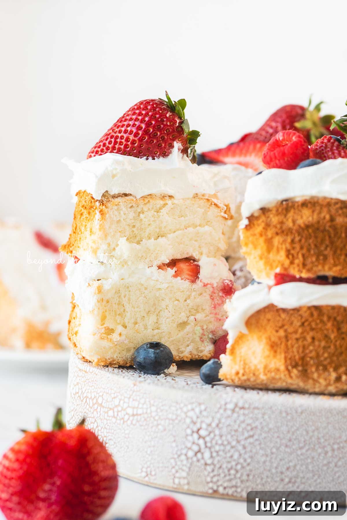 Light and Fluffy Homemade Angel Food Cake Recipe 7 Angel food cake with one slice pulled out on a ceramic cake stand