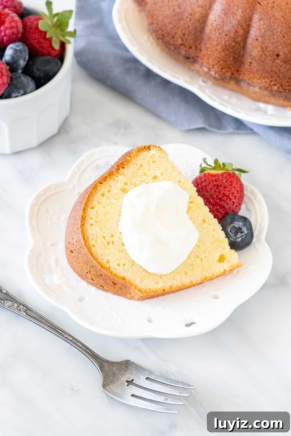 Decadent Cream Cheese Pound Cake Recipe with Vanilla Glaze 6 Slice of pound cake with whipped cream and berries