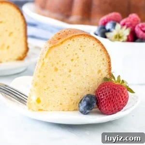 Decadent Cream Cheese Pound Cake Recipe with Vanilla Glaze 7 Slice of moist pound cake with berries on a plate.