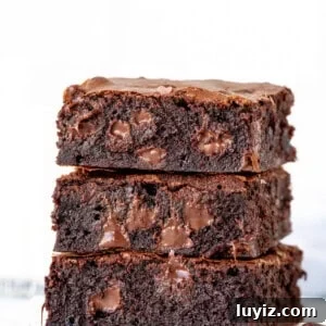 Ultimate Triple Chocolate Brownies Recipe: Decadent Fudgy Squares 5 Stack of three gooey brownies with melted chocolate chips