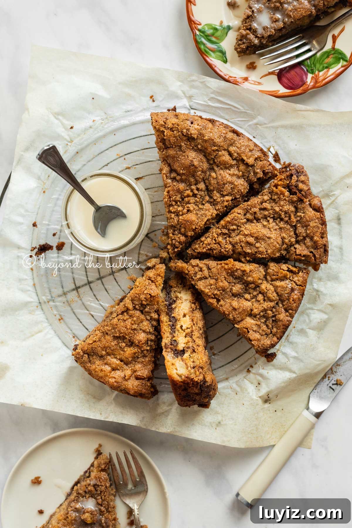 Apple Cinnamon Coffee Cake Recipe for Moist, Tender Crumbs 6 Slices of apple coffee cake on top of a parchment paper lined wire cooling rack with a small jar of simple vanilla glaze next to it | All Images © Beyond the Butter™