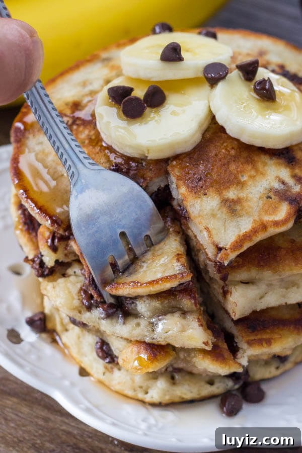 Fluffy Banana Chocolate Chip Pancakes Recipe 5 A stack of extra fluffy banana chocolate chip pancakes drizzled with syrup