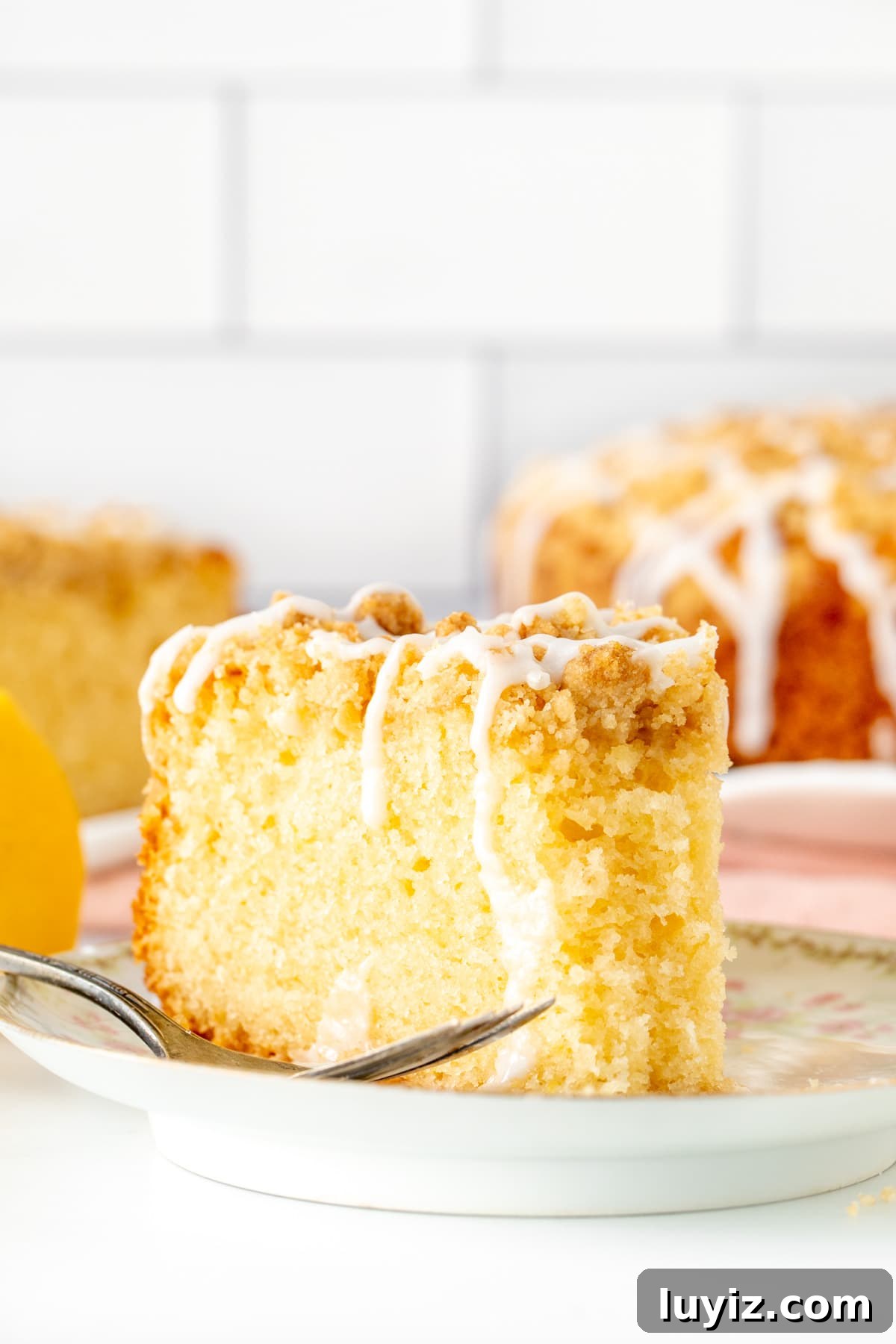 Moist Lemon Coffee Cake Recipe with Zesty Glaze 7 Slice of lemon coffee cake with crumb topping with a bite taken out