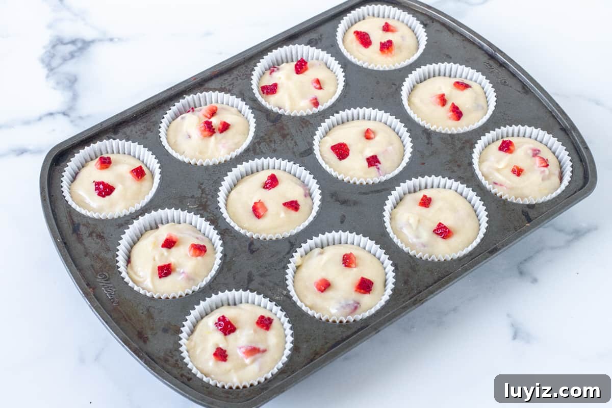 Fluffy Strawberry Muffins with Fresh Berries and Vanilla 7 Muffin tin filled with strawberry muffin batter.
