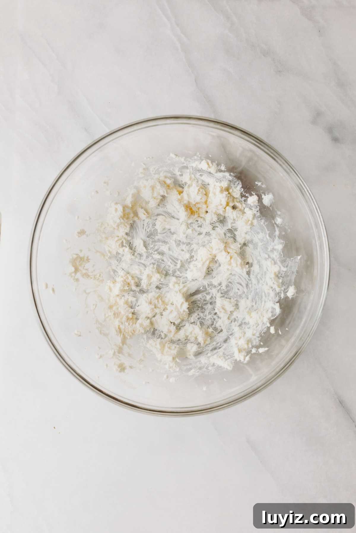Pumpkin Whoopie Pies Recipe: Soft Spiced Sandwich Cookies 13 Whisked unsalted butter and cream cheese in a glass mixing bowl on a light grey marbled background.