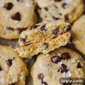 Classic Chocolate Chip Shortbread Cookies Recipe 14 Salted chocolate chip shortbread cookies randomly placed on cookie sheet with the center cookie in half to show the middle.