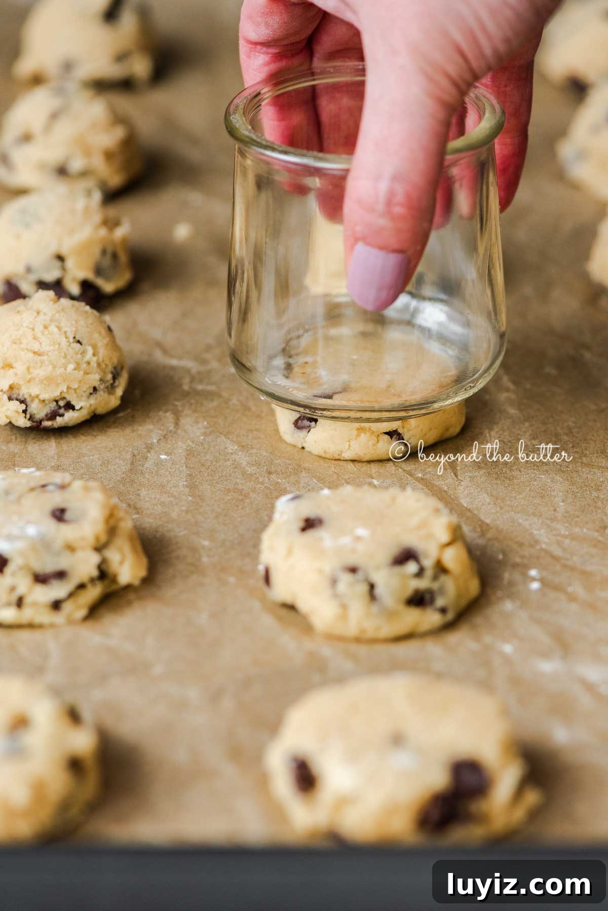 Classic Chocolate Chip Shortbread Cookies Recipe 3 Flattening the chocolate chip shortbread cookie dough with a small glass jar | All Images © Beyond the Butter®