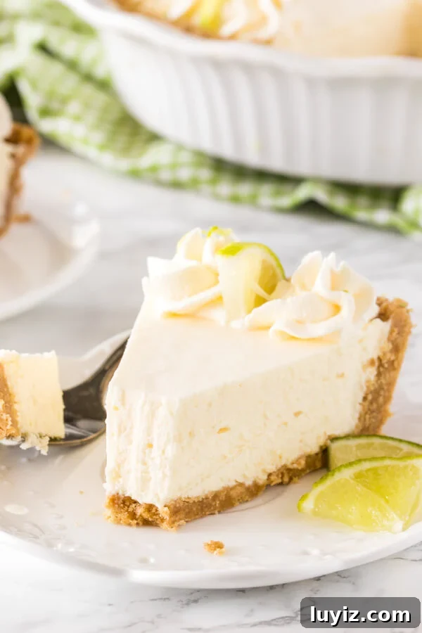 No-Bake Key Lime Pie Recipe (Quick, Creamy & Zesty) 6 A slice of key lime pie on a white plate with a bite taken out to show the creamy texture.