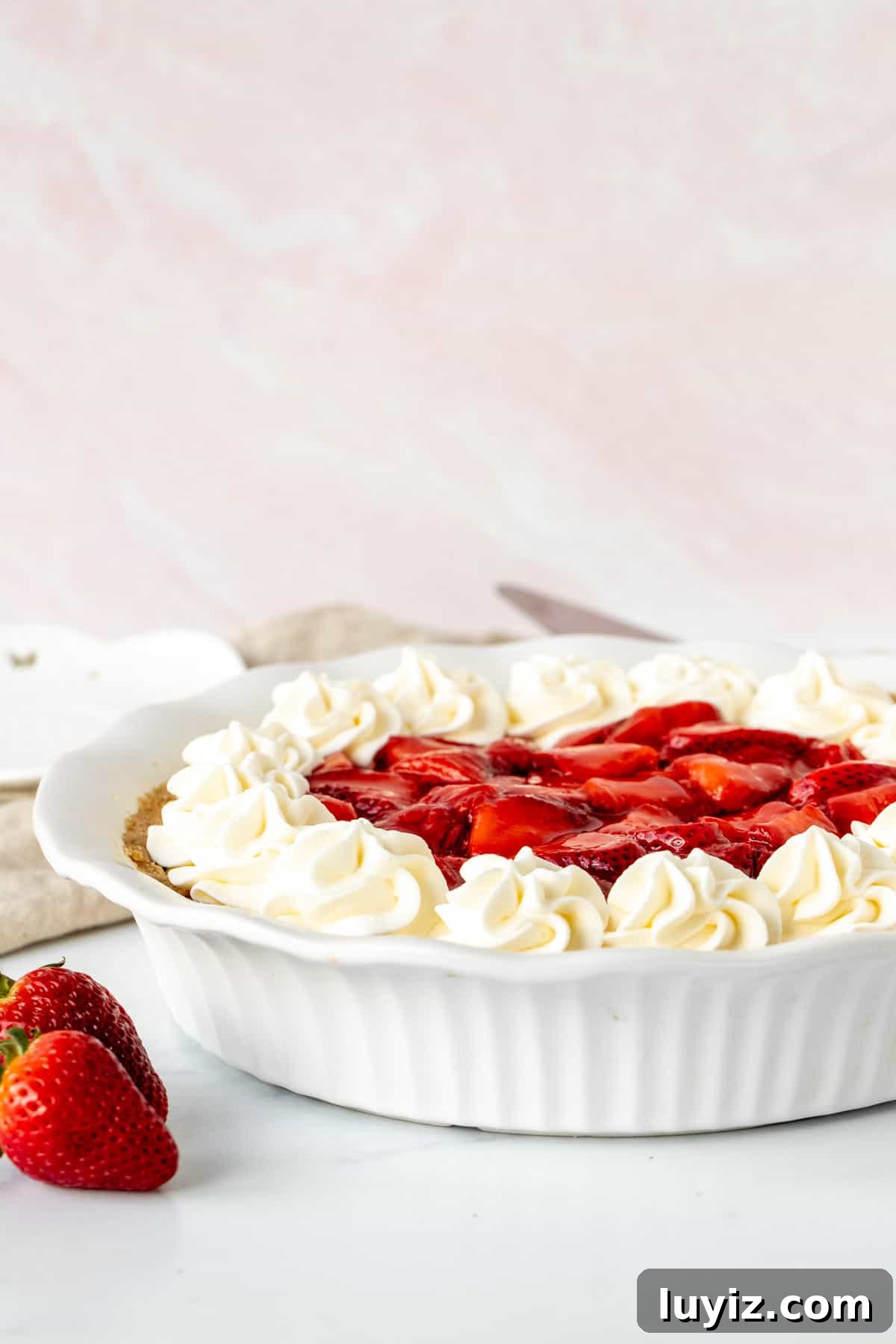 Strawberry Cream Cheese Pie Recipe with Fresh Berry Topping 2 Strawberry cream cheese pie topped with whipped cream in a white pie plate