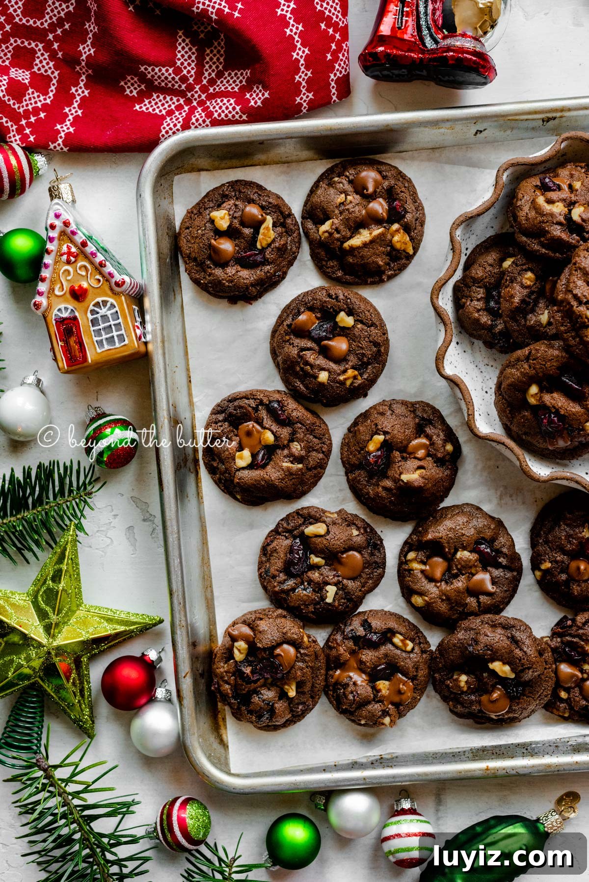 Dark Chocolate Cranberry Walnut Cookie Recipe for Holidays 5 Parchment paper lined baking sheet with dark chocolate cranberry walnut cookies surrounded Christmas tree ornaments | All Images © Beyond the Butter®