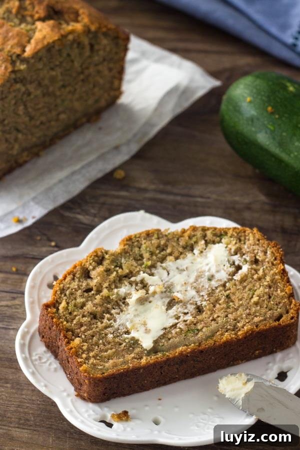 Moist Zucchini Banana Bread Recipe for Summer Baking 6 A slice of zucchini banana bread slathered with butter on a white plate.