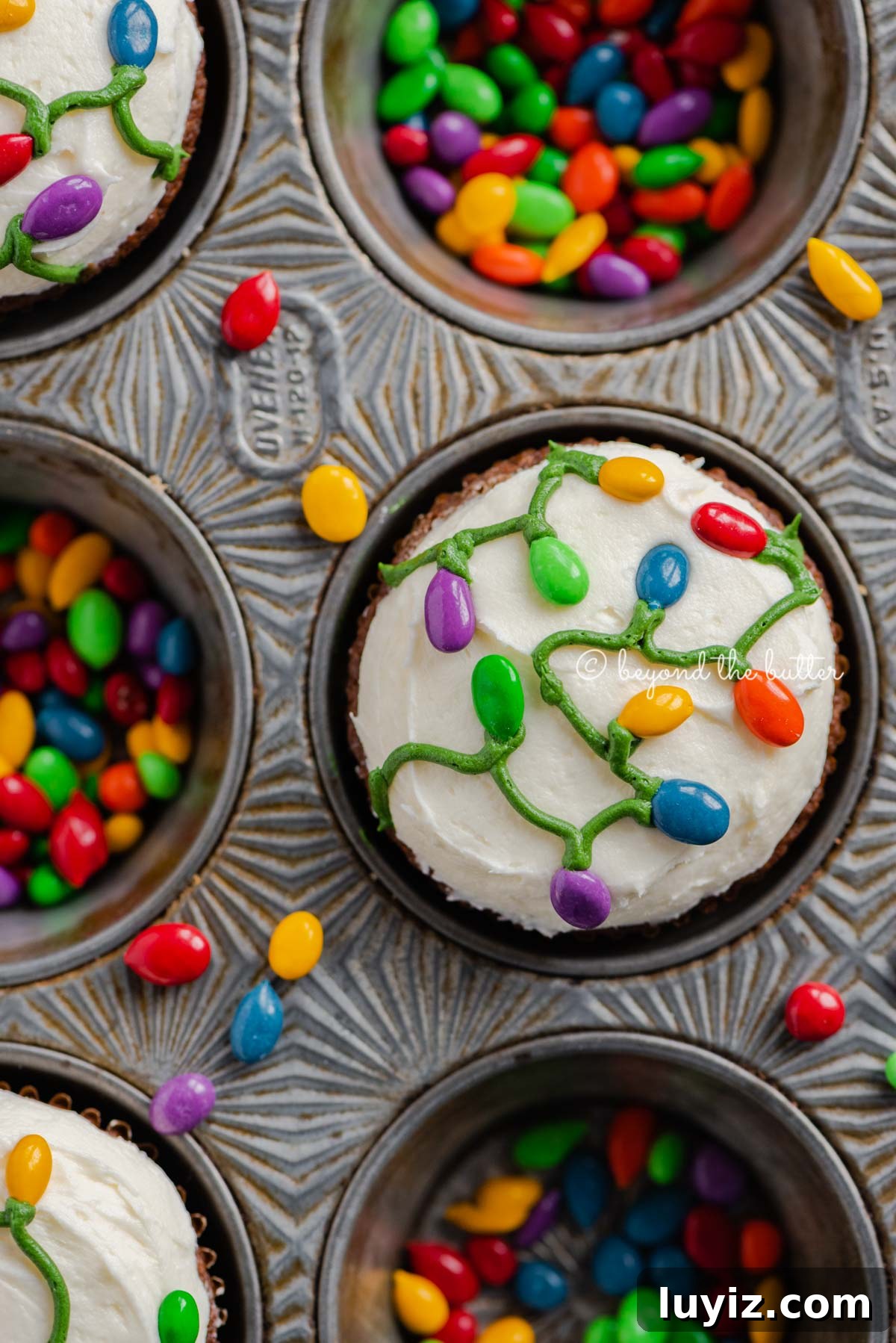 Gingerbread Cupcakes Recipe for a Small Batch (6 Muffins) 4 Cupcake tin with decorated small batch gingerbread cupcakes with marshmallow frosting and rainbow chocolate covered sunflower seeds | All Images © Beyond the Butter®