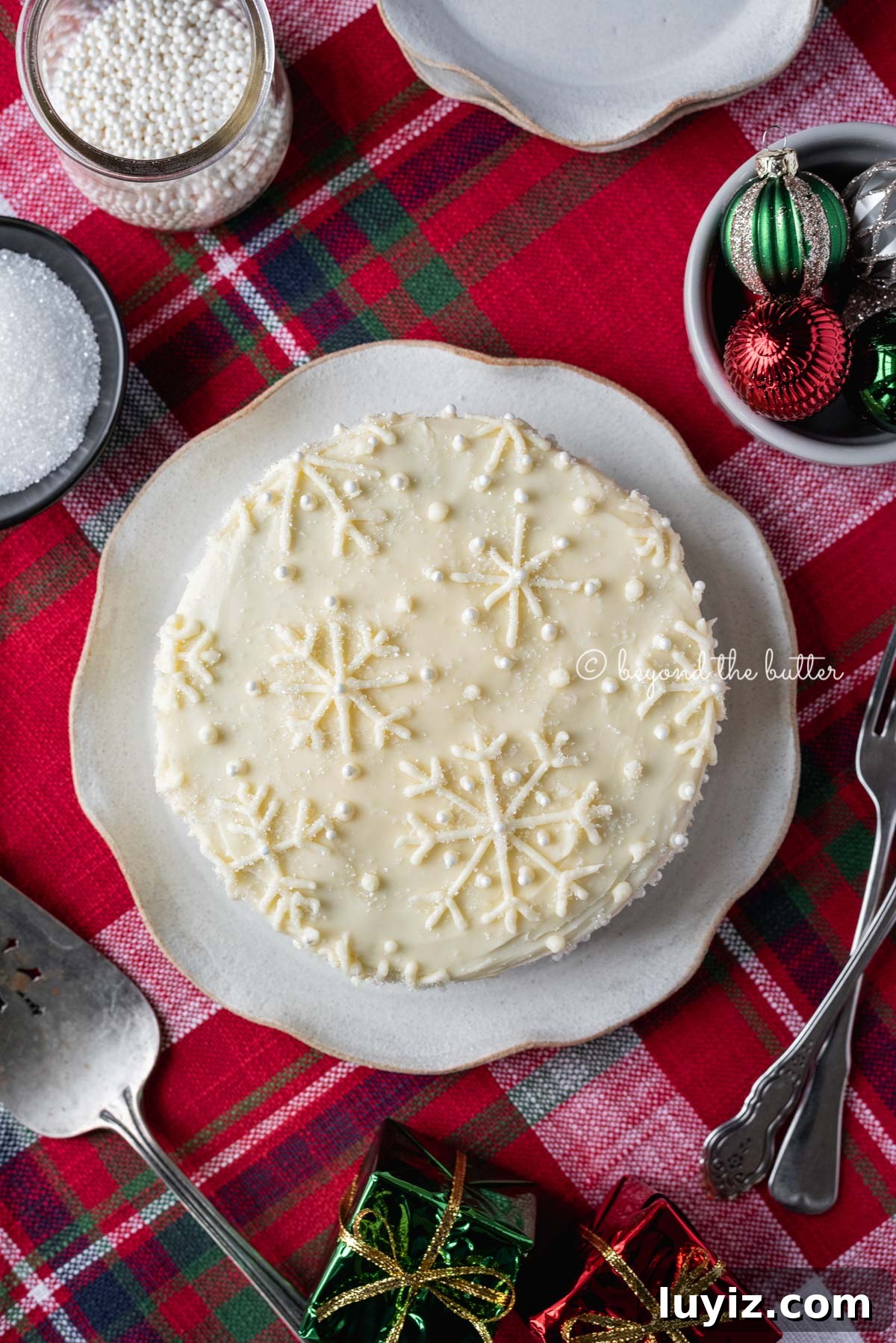 Simple Single-Layer Red Velvet Cake Recipe for Perfect Results 2 Red velvet cake with cream cheese frosting on a scalloped edge dessert plate with red plaid background | All Images © Beyond the Butter®