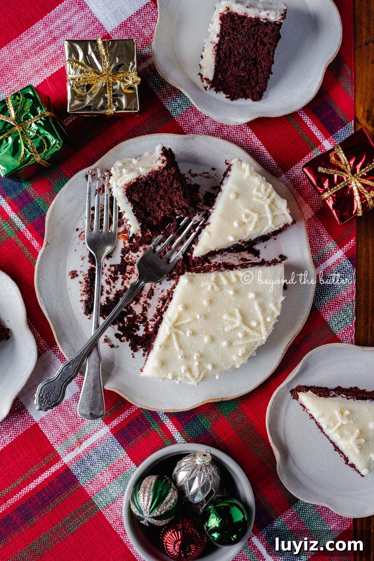 Simple Single-Layer Red Velvet Cake Recipe for Perfect Results 5 Half eaten and sliced red velvet cake with cream cheese frosting on a scalloped edge dessert plate with red plaid background | All Images © Beyond the Butter®