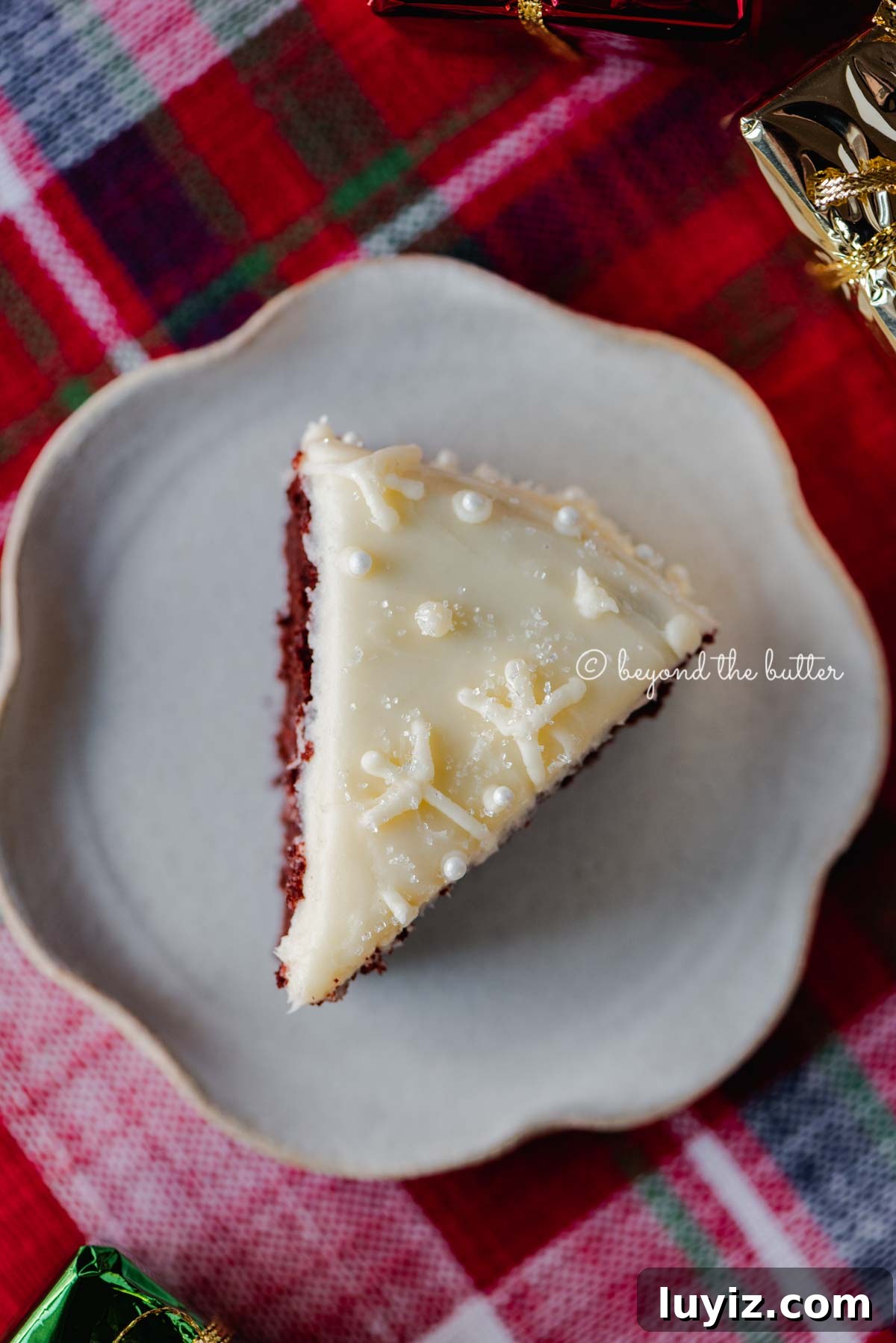 Simple Single-Layer Red Velvet Cake Recipe for Perfect Results 7 Slice of red velvet cake with cream cheese frosting on a scalloped edge dessert plate with red plaid background | All Images © Beyond the Butter®