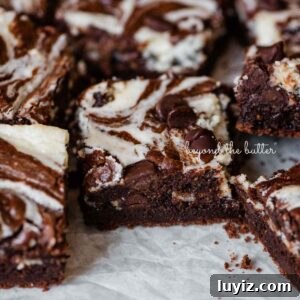 Cream Cheese Swirled Chocolate Chip Brownies 22 Sliced chocolate chip cream cheese brownies on parchment paper.