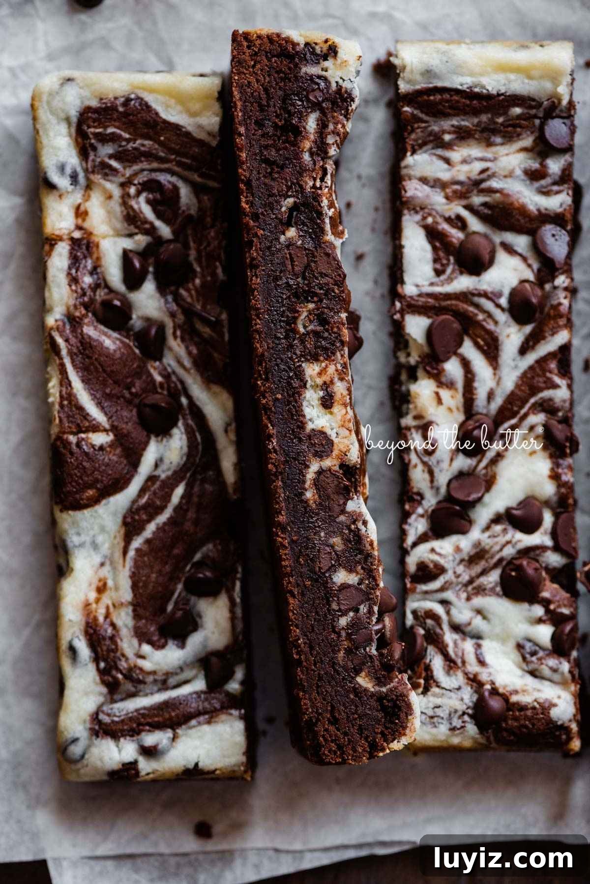 Cream Cheese Swirled Chocolate Chip Brownies 6 Chocolate chip cream cheese brownies cut into bars on parchment paper.