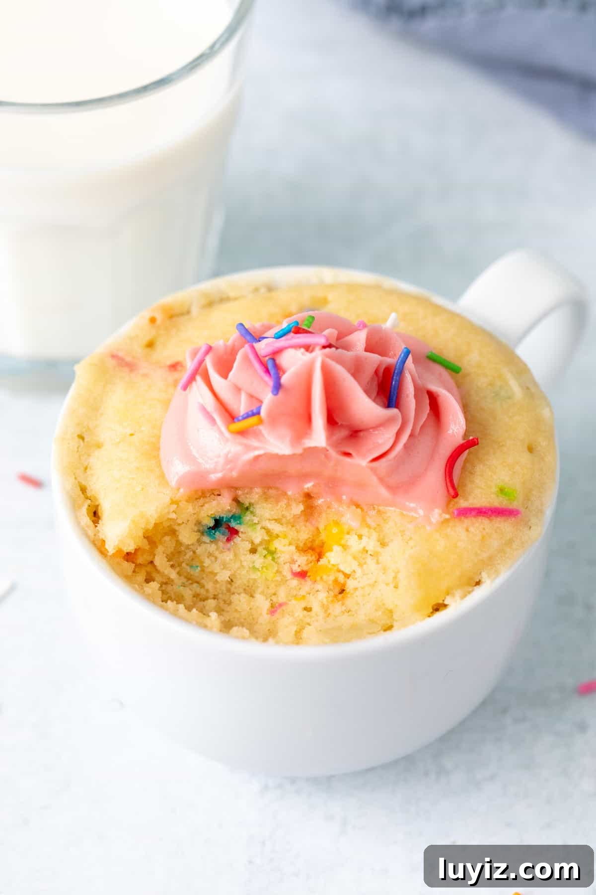 Quick Vanilla Mug Cake Recipe for One — Ready in Minutes 7 Sprinkle mug cake topped with vanilla frosting, with a spoonful taken out