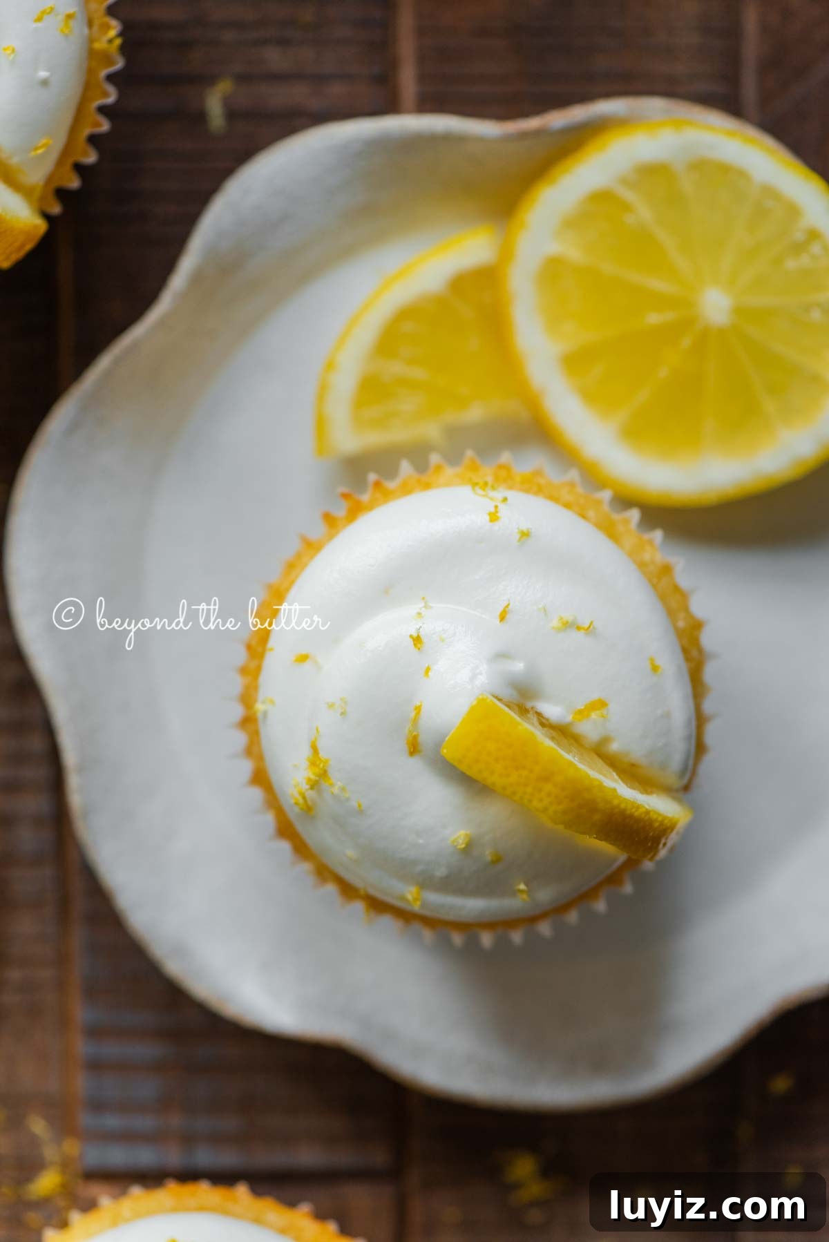 Mini Lemon Cupcakes: Perfect Small-Batch Recipe for 6-8 Servings 11 Lemon cupcake with lemon cream cheese frosting garnished with lemons on a small wavy dessert plate