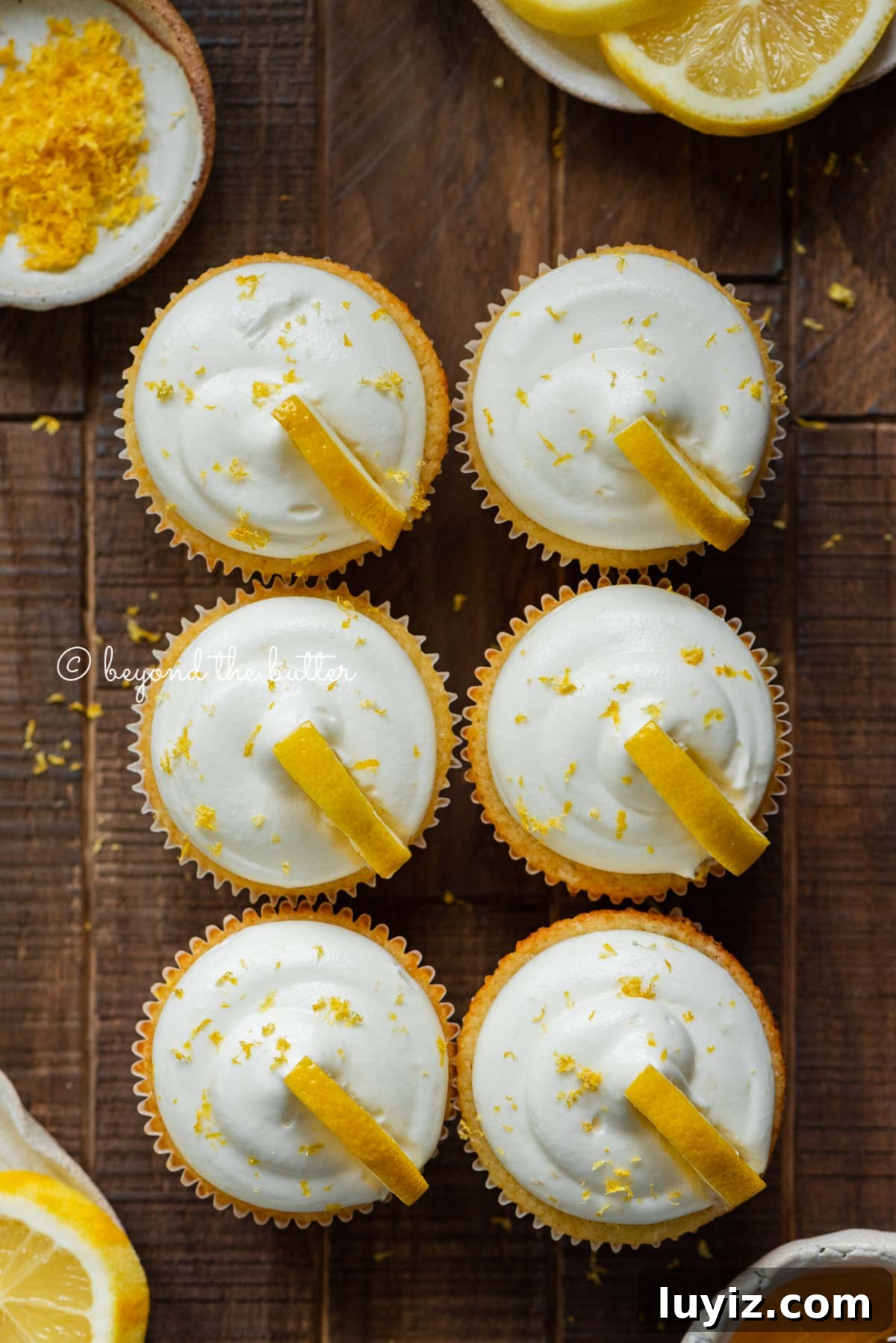 Mini Lemon Cupcakes: Perfect Small-Batch Recipe for 6-8 Servings 4 Two rows of small batch lemon cupcakes with lemon cream cheese frosting and garnished with lemon triangles on a dark wood background