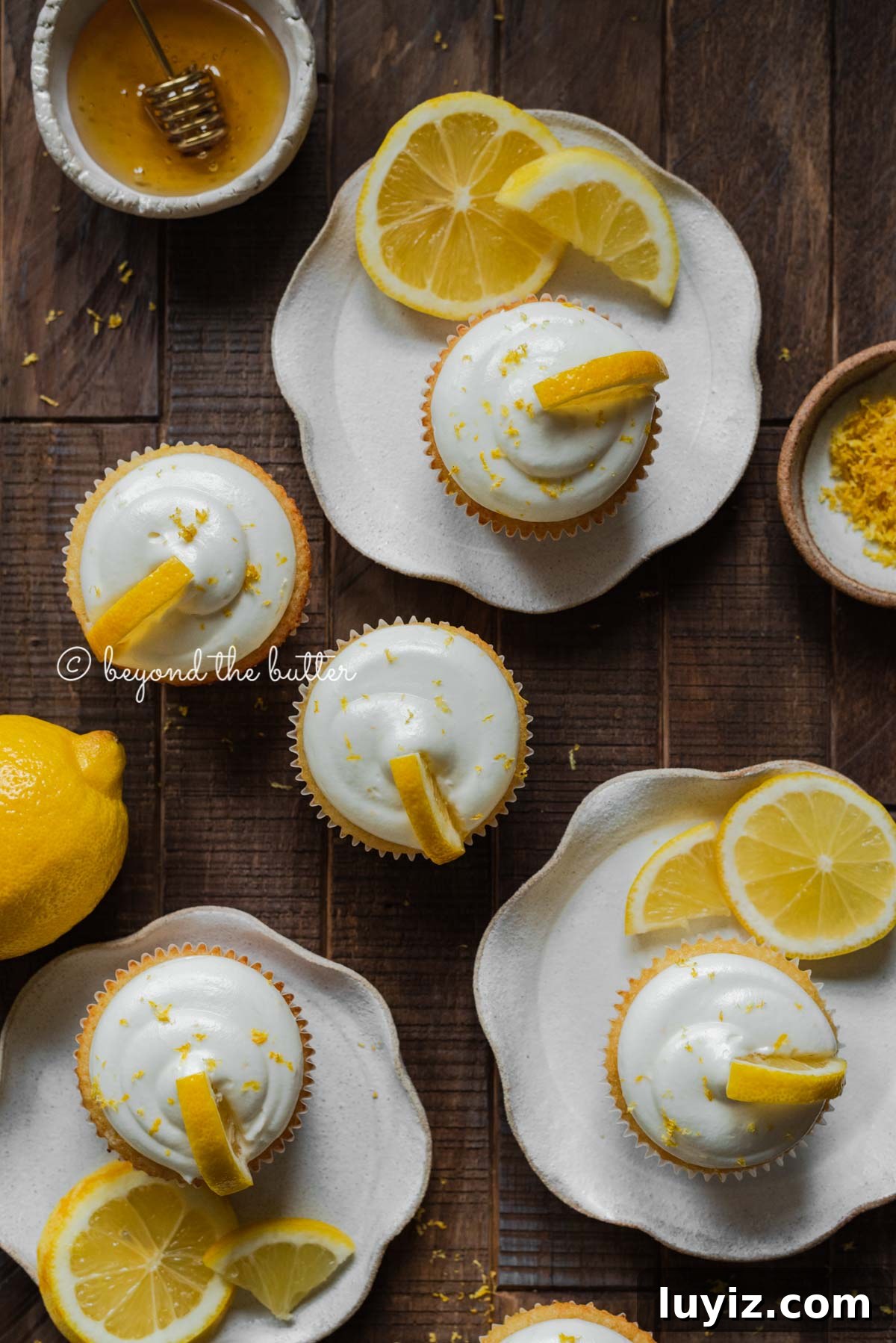 Mini Lemon Cupcakes: Perfect Small-Batch Recipe for 6-8 Servings 7 Randomly placed lemon cupcakes with lemon cream cheese frosting, garnished with lemon triangles on a dark wood background