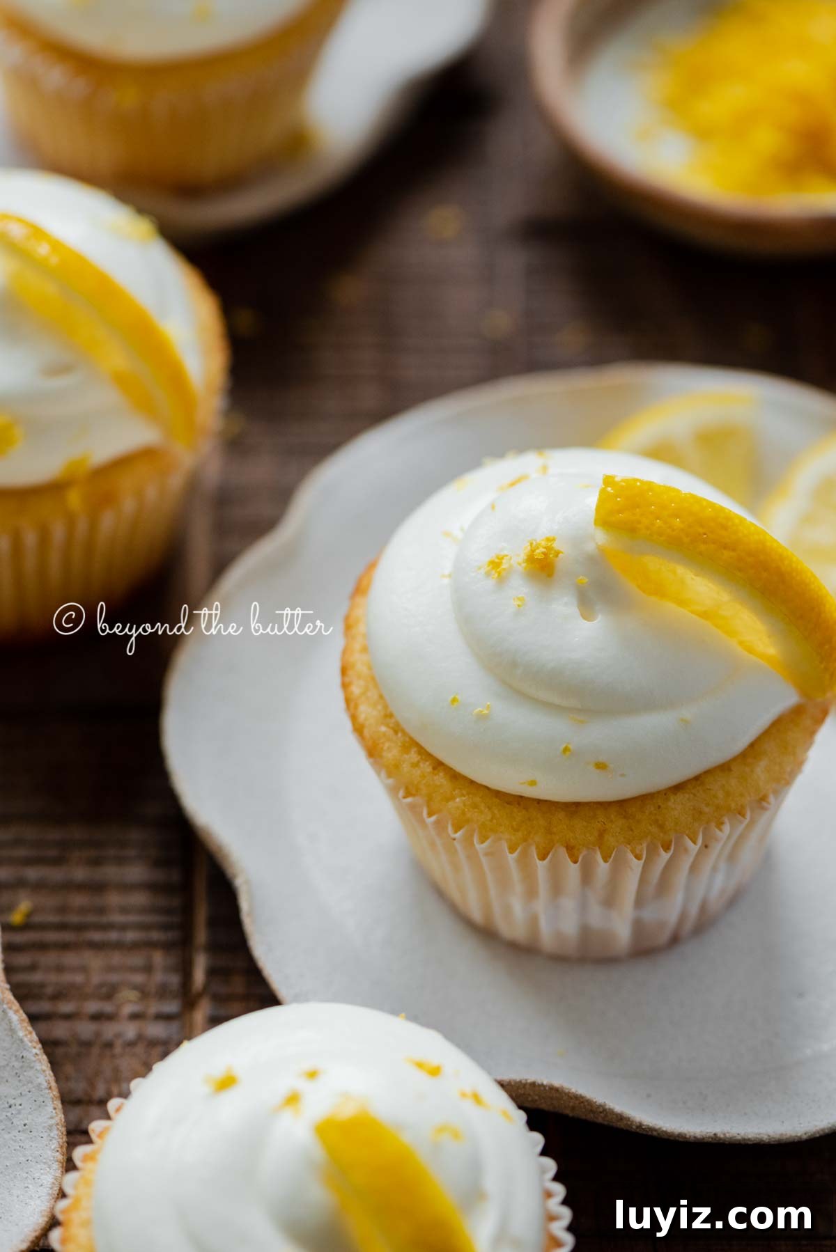Mini Lemon Cupcakes: Perfect Small-Batch Recipe for 6-8 Servings 9 Lemon cupcakes with lemon cream cheese frosting garnished with lemons on small wavy dessert plates