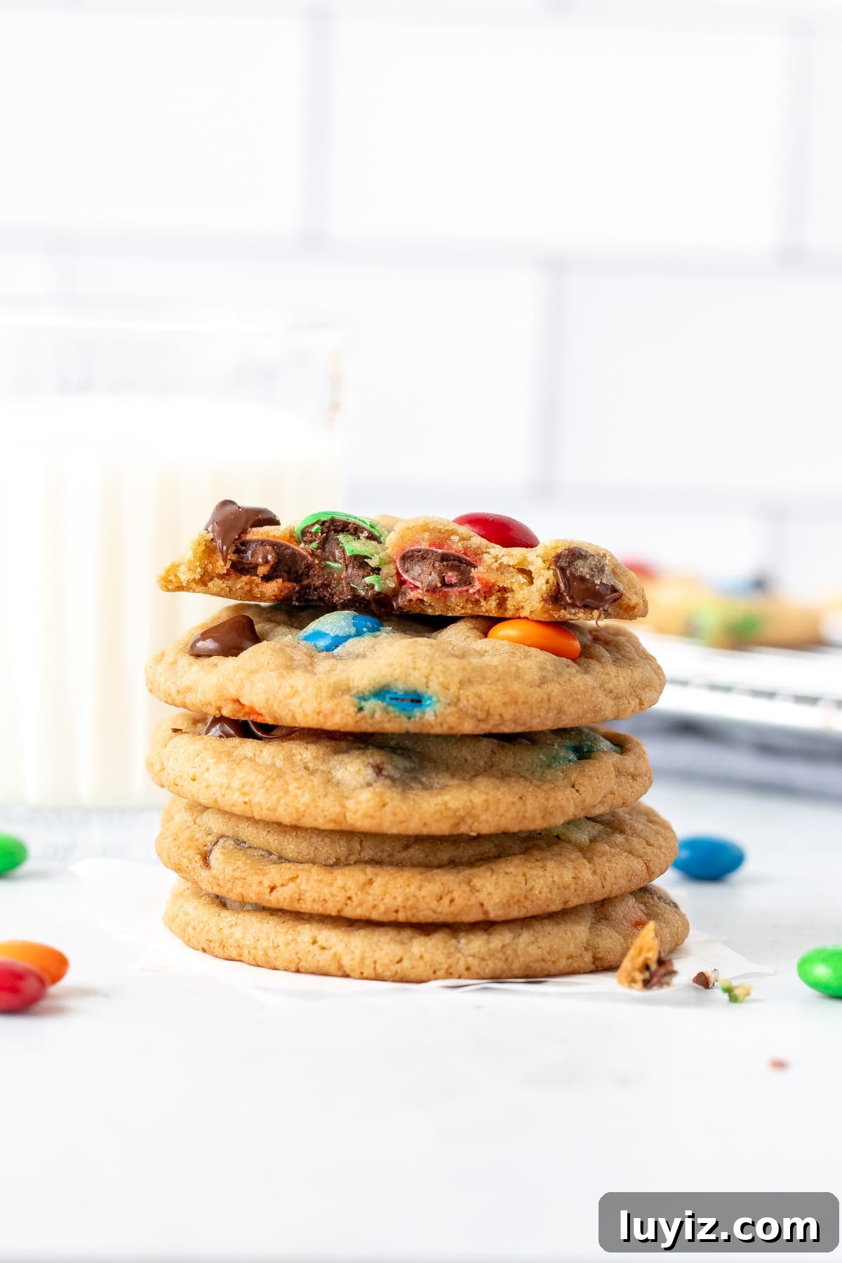 Soft & Chewy M&M Cookies That Melt in Your Mouth 8 Stack of M&M chocolate chip cookies with a glass of milk