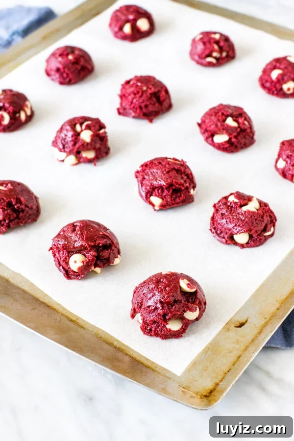 Red Velvet Cake Mix Cookies Recipe — Soft, Chewy Treats 3 Lined cookie sheet with cookie dough balls.