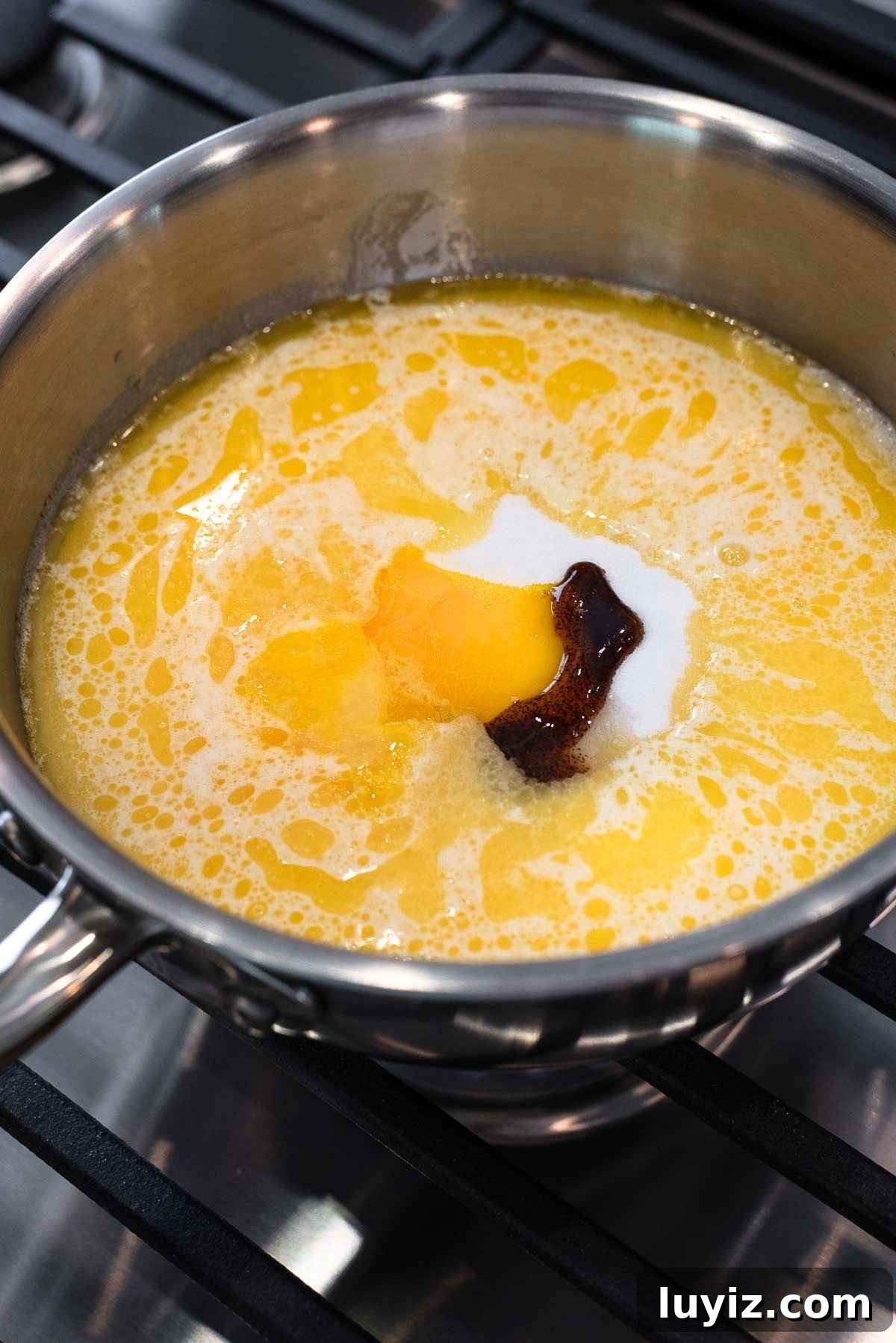 Butter, evaporated milk, sugar, vanilla extract, rum extract, and slightly whisked egg yolks added to a stainless steel saucepan.