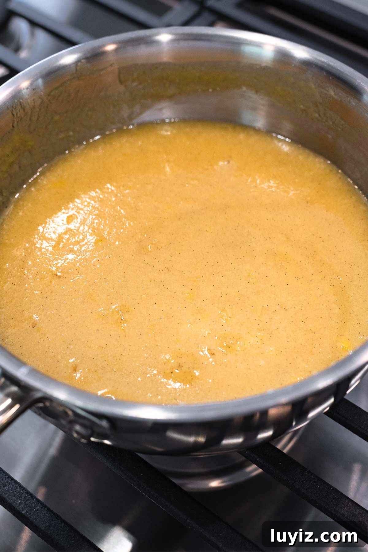 Thickened butter, evaporated milk, egg yolks, sugar, and extracts in a stainless steel saucepan.