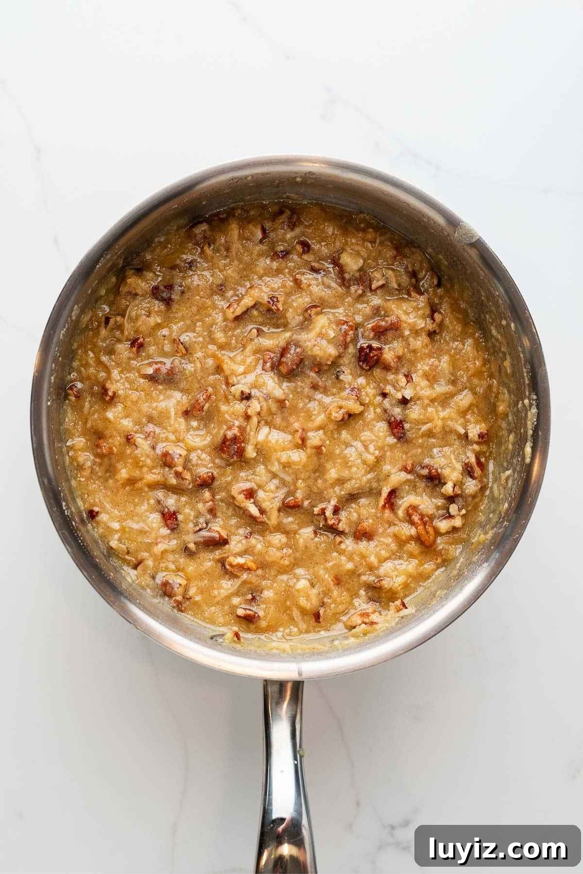 Toasted unsweetened coconut flakes and toasted, chopped pecans added to the coconut pecan frosting mixture.
