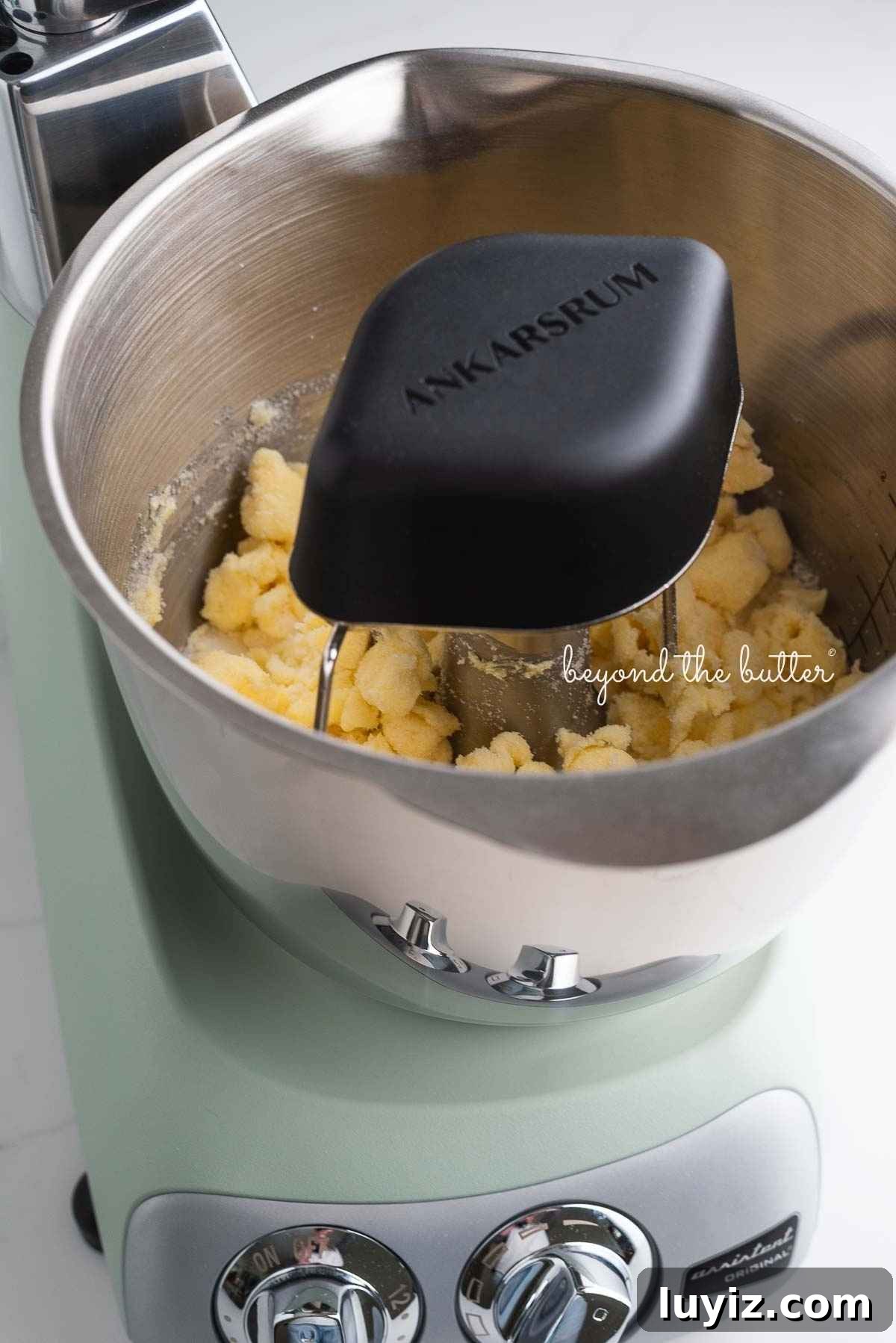 Ankarsrum assistent original mixer in nordic sage mixing butter and sugar together using the premium beater set and cookie whisks.