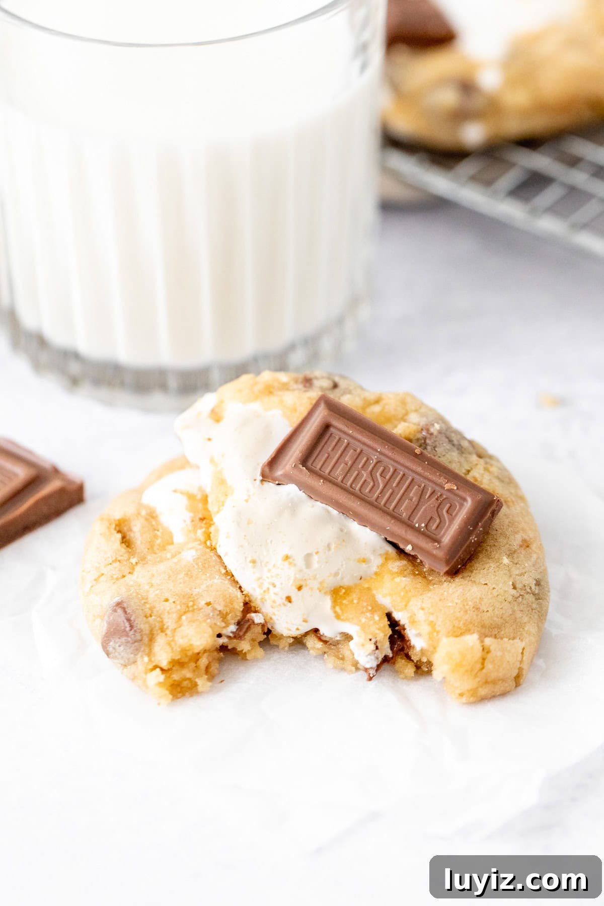 S'mores stuffed cookie, broken in half with a glass of milk