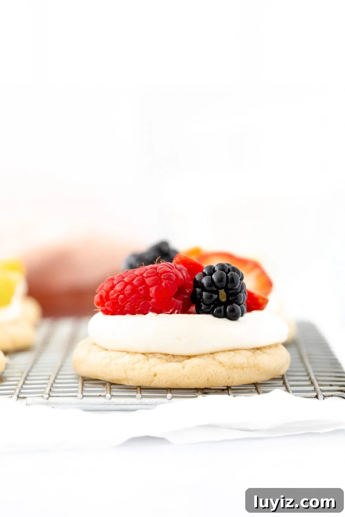 Mini Fruit Pizza Bites: Party Dessert Recipe 2 mini fruit pizza topped with berries on a cooling rack