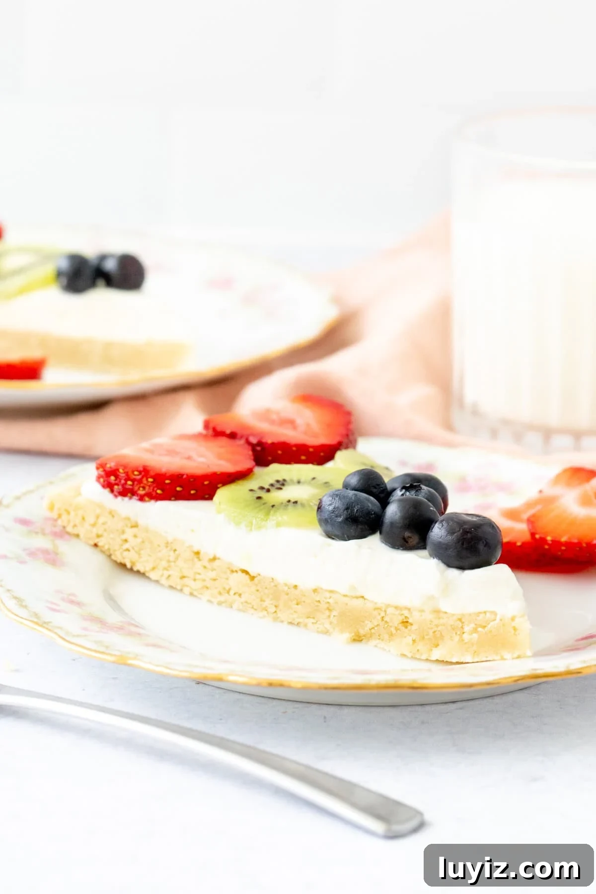 Slice of fruit pizza topped with whipped cream cheese frosting and fruit