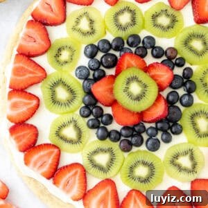 fruit pizza with sugar cookie crust, cream cheese frosting and fresh fruit