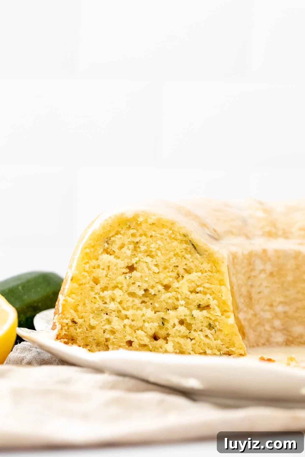 Moist Lemon Zucchini Cake with Lemon Glaze 9 Lemon zucchini bundt cake on a white plate with slices cut out
