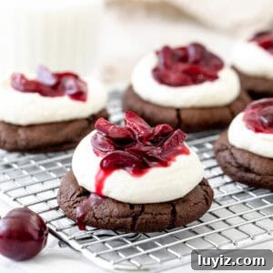 black forest cookies with whipped cream and cherry sauce on a cooling rack