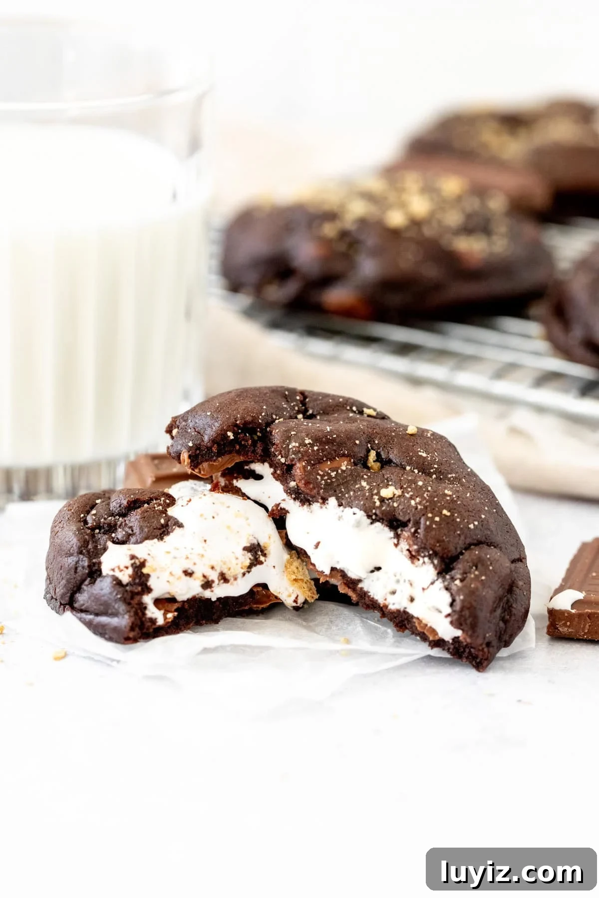 Gooey S'mores Chocolate Cookies Recipe 6 chocolate cookie stuffed with marshmallow, broken in half with a glass of milk