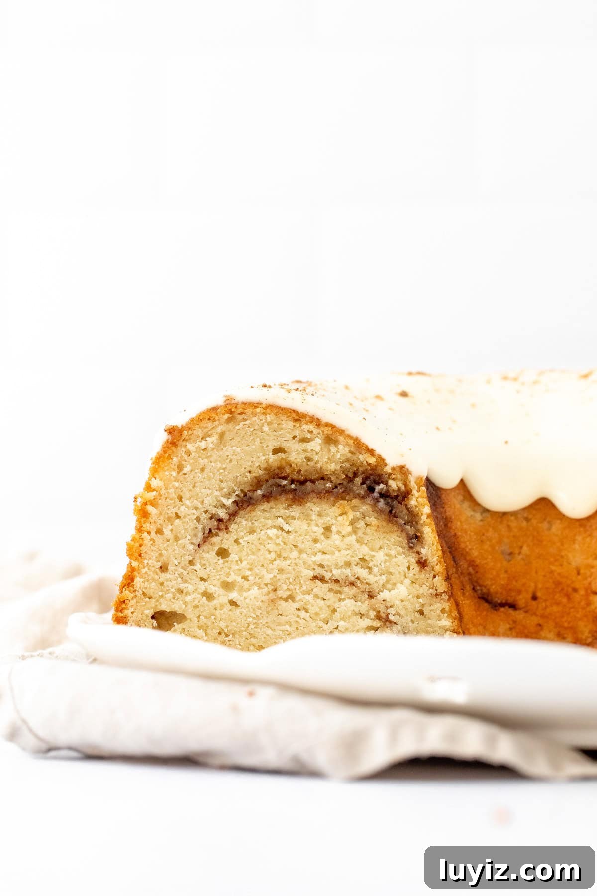 Cinnamon Swirl Bundt Cake with Cream Cheese Glaze 7 Cinnamon swirl bundt cake with cream cheese icing on a white plate, with slices cut out